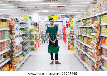 Full-length portrait of young Hispanic with basket man in a supermarket