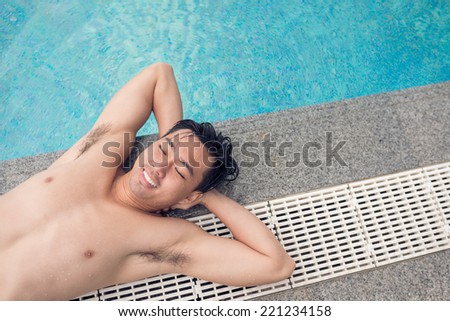 Young man sunbathing on the poolside, view from the top