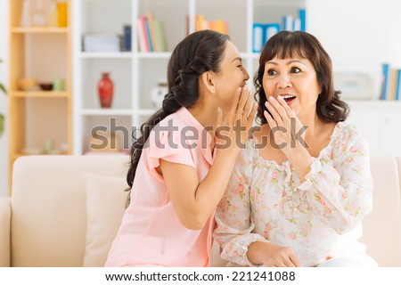 Mature woman telling a secret to her surprised friend