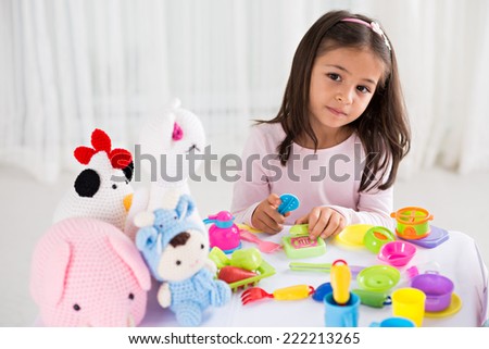 Little girl playing with toy dishware and knitted toys