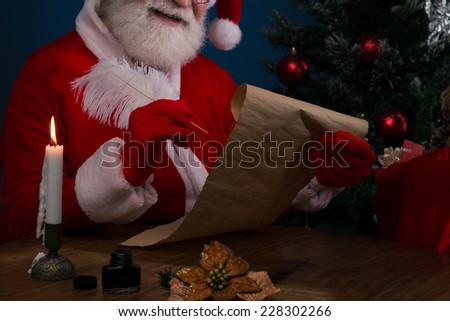 Cropped image of smiling Santa writing list of names