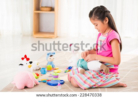 Asian little girl playing with knitted toys