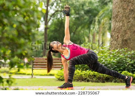 Vietnamese girl exercising in park doing revolved side angle pose
