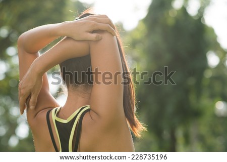 Rear view of woman stretching her arm and shoulder