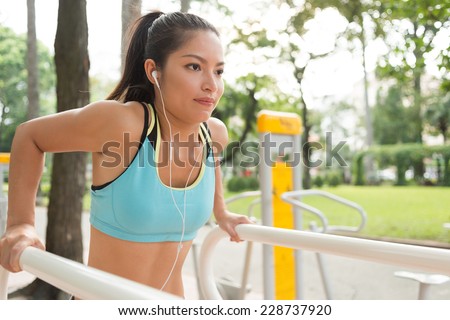 Sporty girl doing parallel bar dips to the music