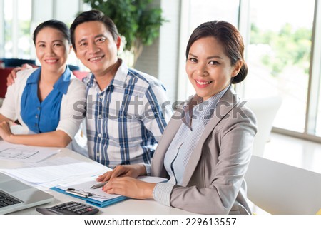 Smiling saleswoman on the background of happy Vietnamese family