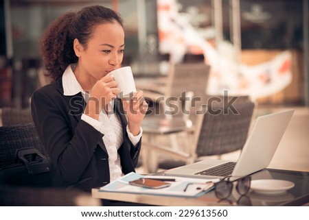 Business lady drinking coffee and working on laptop in the cafe