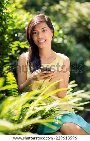 Pretty lady text messaging while sitting outdoors