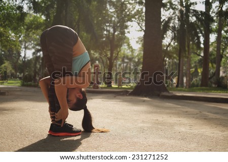 Sporty woman sportswoman doing a standing forward bend in the park