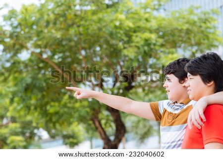 Young boy hugging his brother and pointing away