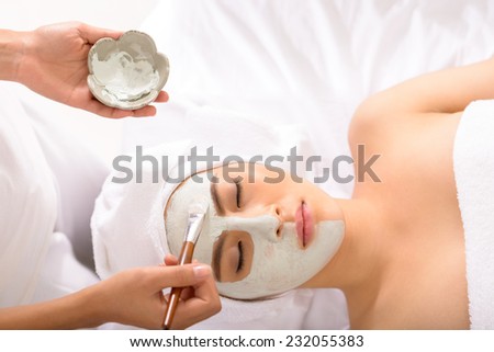 Beautician applying facial mask to the young lady, view from the top