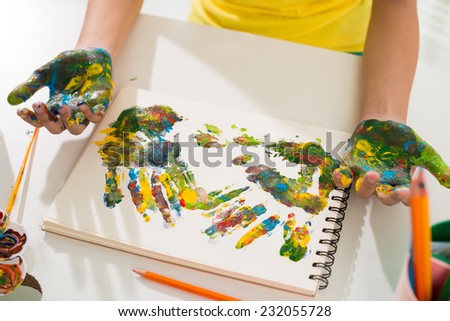 Hands of girl making multicolored hand prints