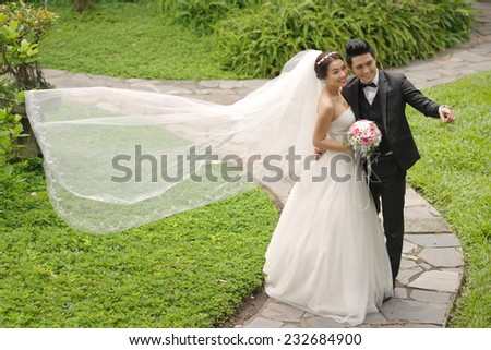 Vietnamese wedding couple in the park, groom showing something to his bride