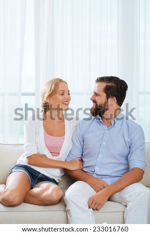 Loving husband and wife sitting on the sofa and looking at each other