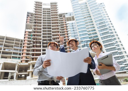 Team of architects comparing housing project with the building