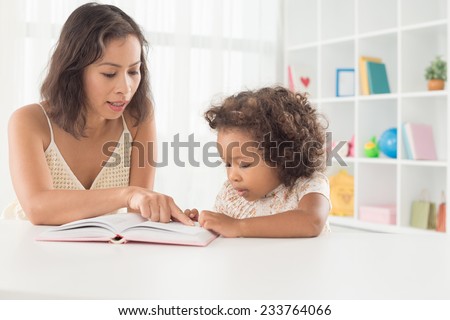 Woman and her little daughter reading together