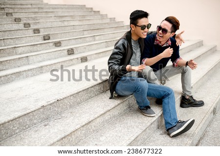 Best friends in sunglasses sitting on the steps and laughing