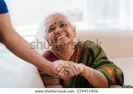 Happy old lady holding a hand of her husband and looking at him