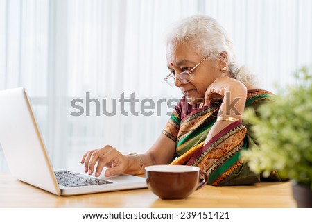 Serious old Indian lady working on laptop