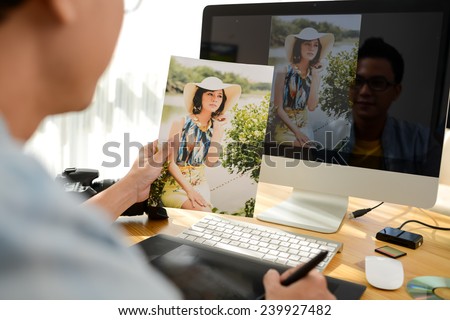 Professional retoucher working on photograph of young woman, view over the shoulder