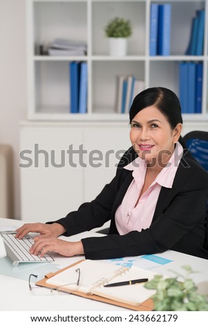 Pretty senior business lady typing on computer