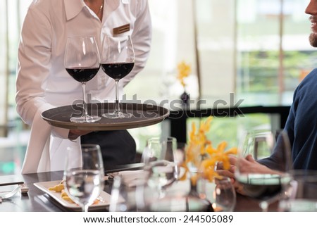 Cropped image of waiter serving drinks in a restaura