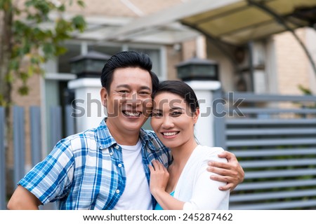 Portrait of happy middle-aged couple with their new house in the background
