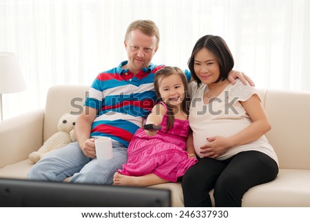 Mixed-race family watching tv together