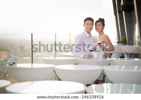 Adorable Vietnamese couple drinking wine in the rooftop restaurant