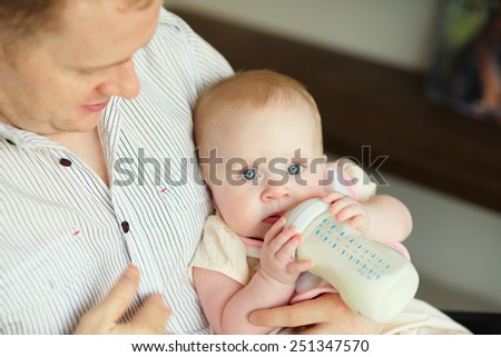 Father feeding cute little daughter from a bottle