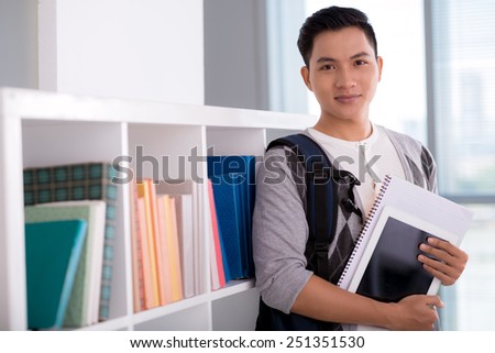 Portrait of Vietnamese student with a digital tablet standing in a library