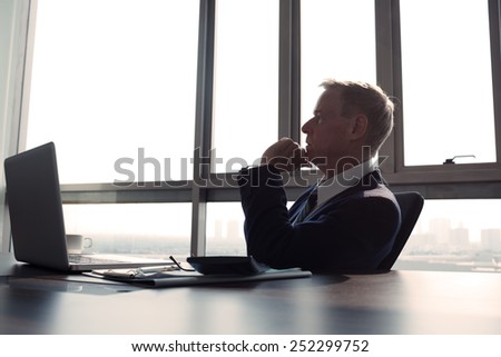 Contemplating businessman in the office, side view