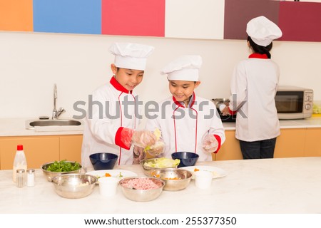 Vietnamese boys in professional uniform cooking in the kitchen
