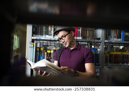Asian student behind a book shelf in the library