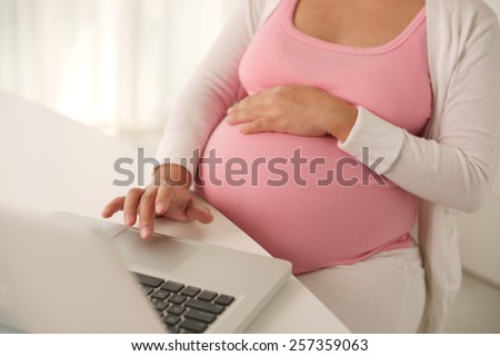 Pregnant woman working on laptop at home