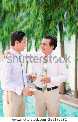 Asian business partners talking and drinking wine