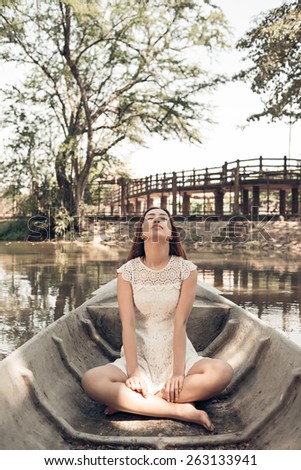 Relaxed young woman sitting in lotus position in a boat