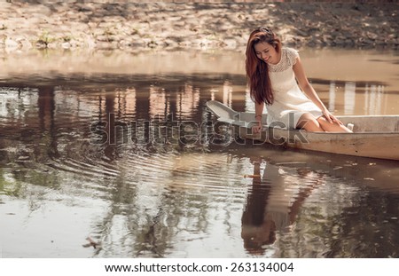 Beautiful woman sitting in boat and looking in the water