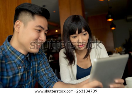 Vietnamese businessman sharing information on the tablet with his colleague