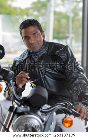 Indian man in leather jacket sitting on motorcycle