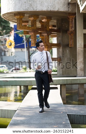 Asian manager with take-out coffee going to work