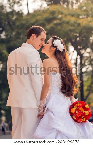 Multi-ethnic wedding couple kissing in the park