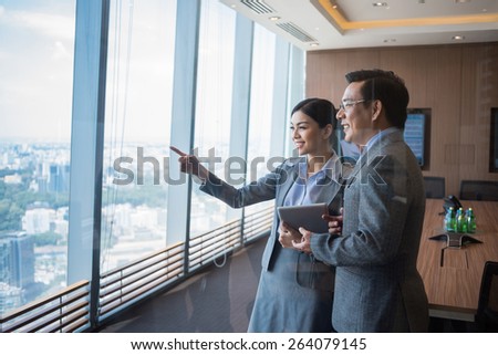Smiling business people looking through the office window