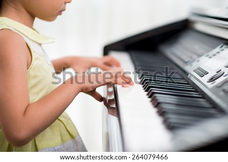 Cropped image of little girl practicing piano