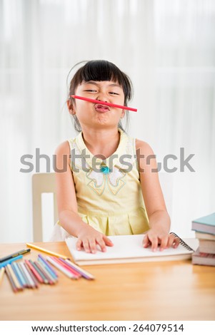 Portrait of playful Vietnamese girl with a pencil between nose and lip
