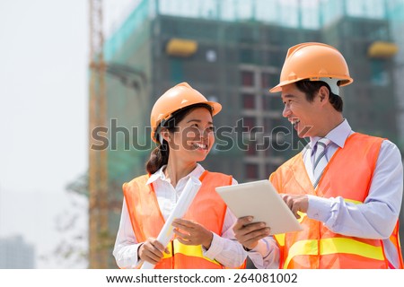 Happy engineer and his female colleague using digital tablet at the construction site