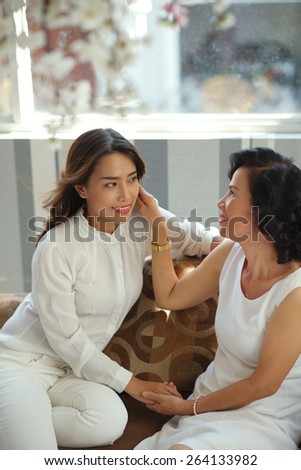 Beautiful young Vietnamese woman and her grown up daughter talking at home