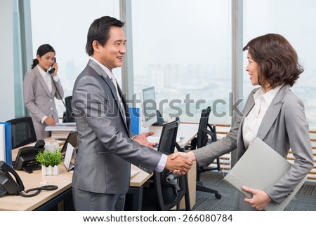 Asian businessman shaking hand of his new female colleague