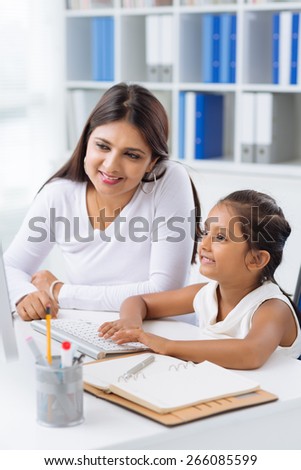 Indian business lady teaching her little daughter to work on computer
