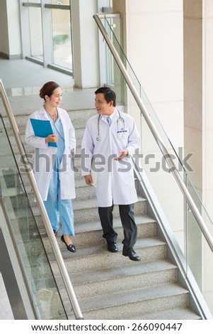Asian medical worker talking while walking down the stairs